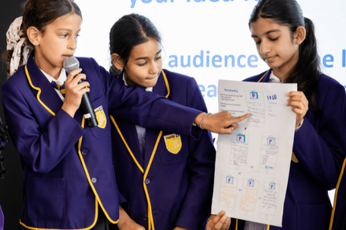 Three primary pupils presenting an app design to an audience