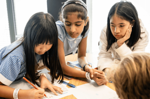 Three female primary pupils working on a project together at a desk