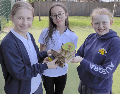 Three primary school pupils holding up a vehicle programmed with a Crumble kit